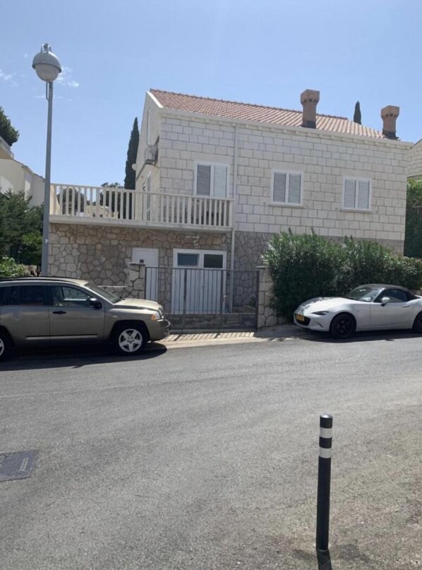 Un edificio de dos pisos con fachada de piedra y techo de tejas. Cuenta con un acceso con reja y un pequeño balcón en la parte superior.