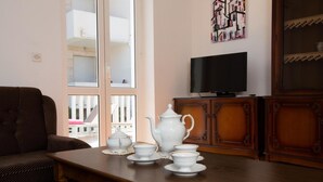 Una sala de estar con un sofá, una mesa de madera con juego de té, un televisor y un aparador.