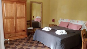 A hotel room with a large wooden wardrobe, a bed with pink and white bedding, and a checkered floor. - B&B Principe Calaf 4 (Lucca)