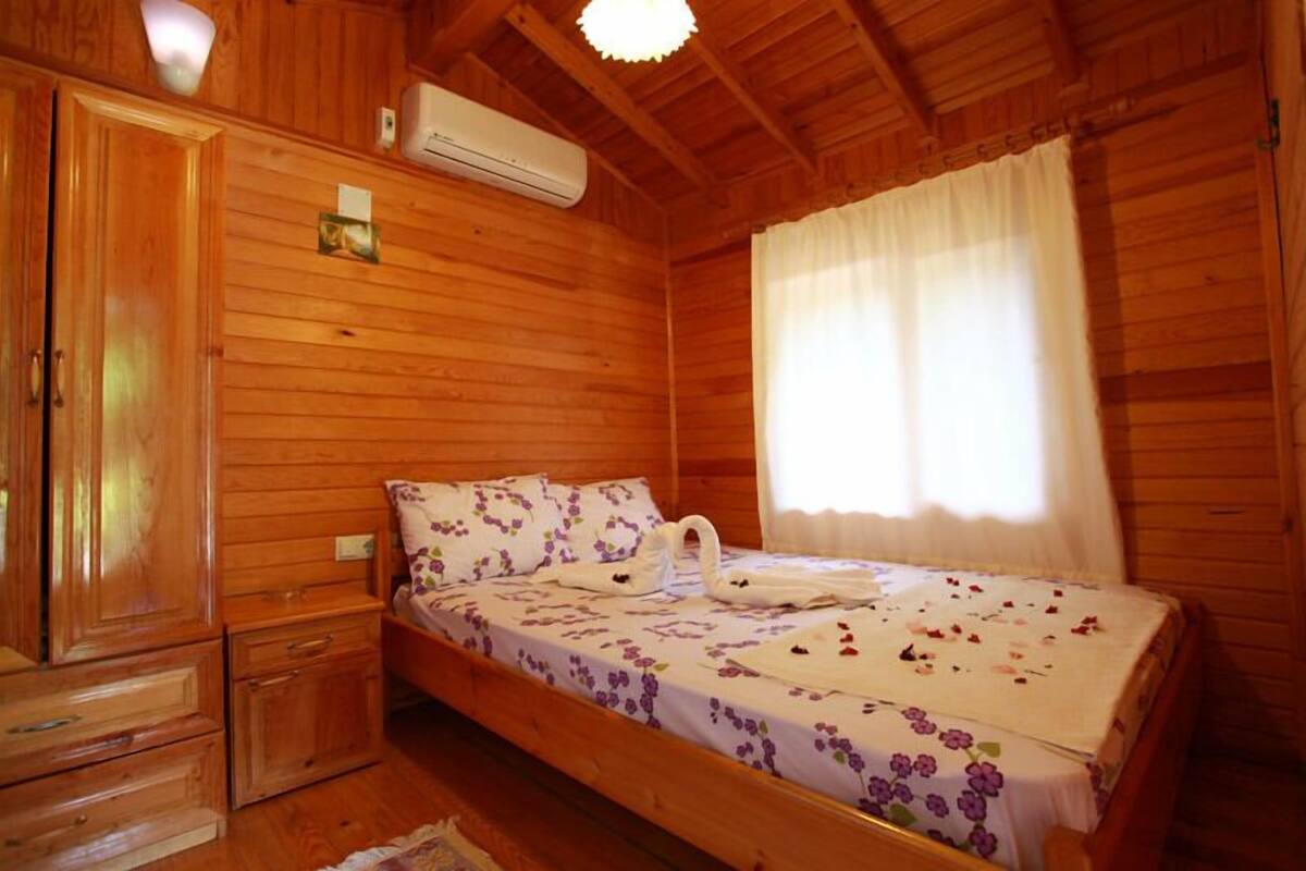 Een houten kamer met een bed, een kledingkast en een raam met gordijnen.