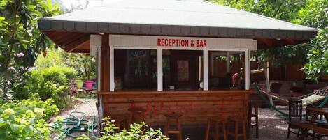 A reception and bar area with wooden furniture and a garden view.