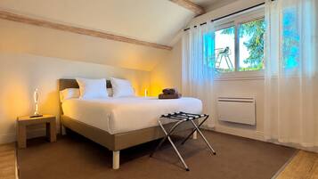 Un dormitorio con cama, mesitas de noche, un radiador y una ventana con cortinas.