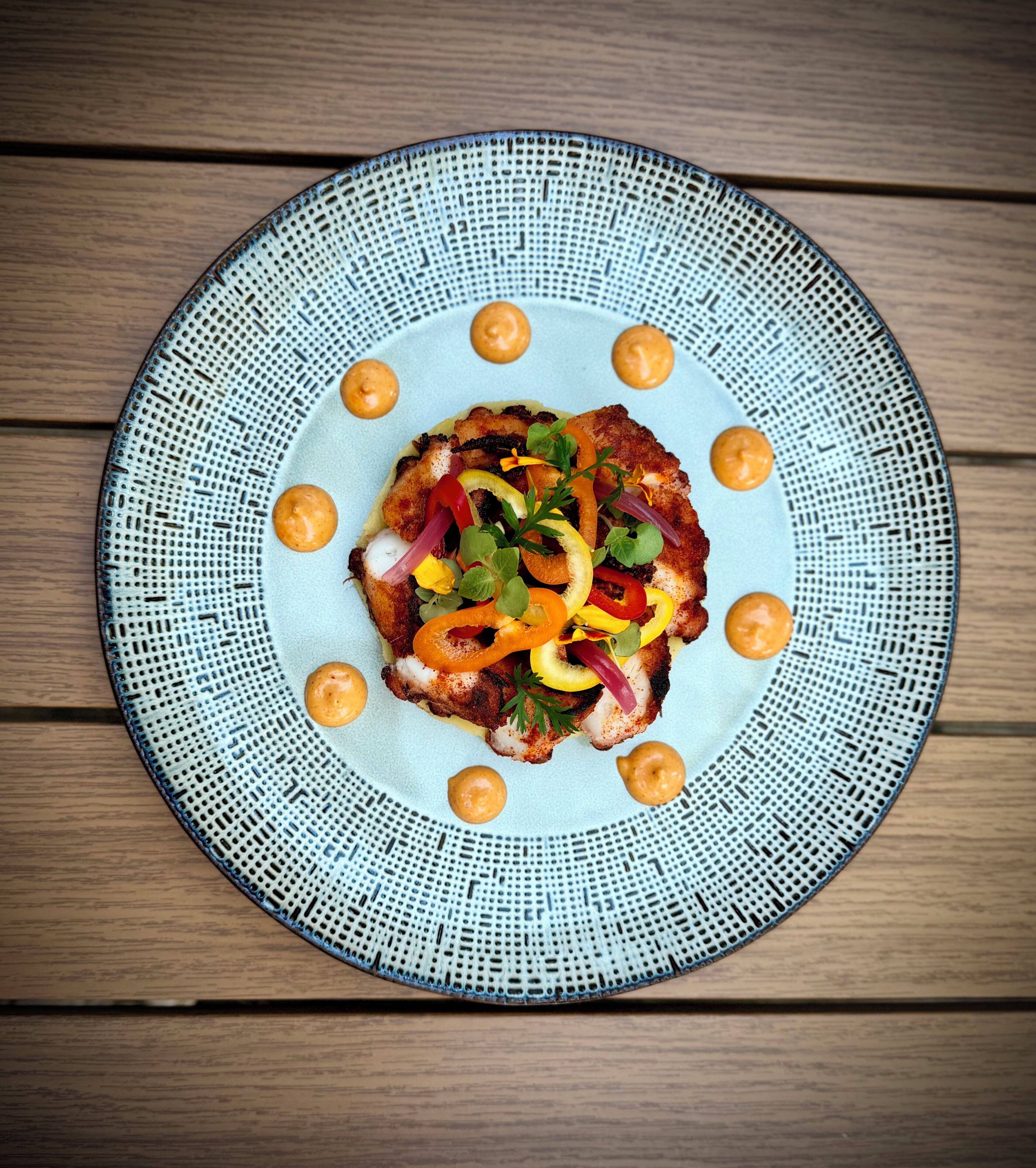 Un plato redondo con borde texturizado, sobre una superficie de madera.