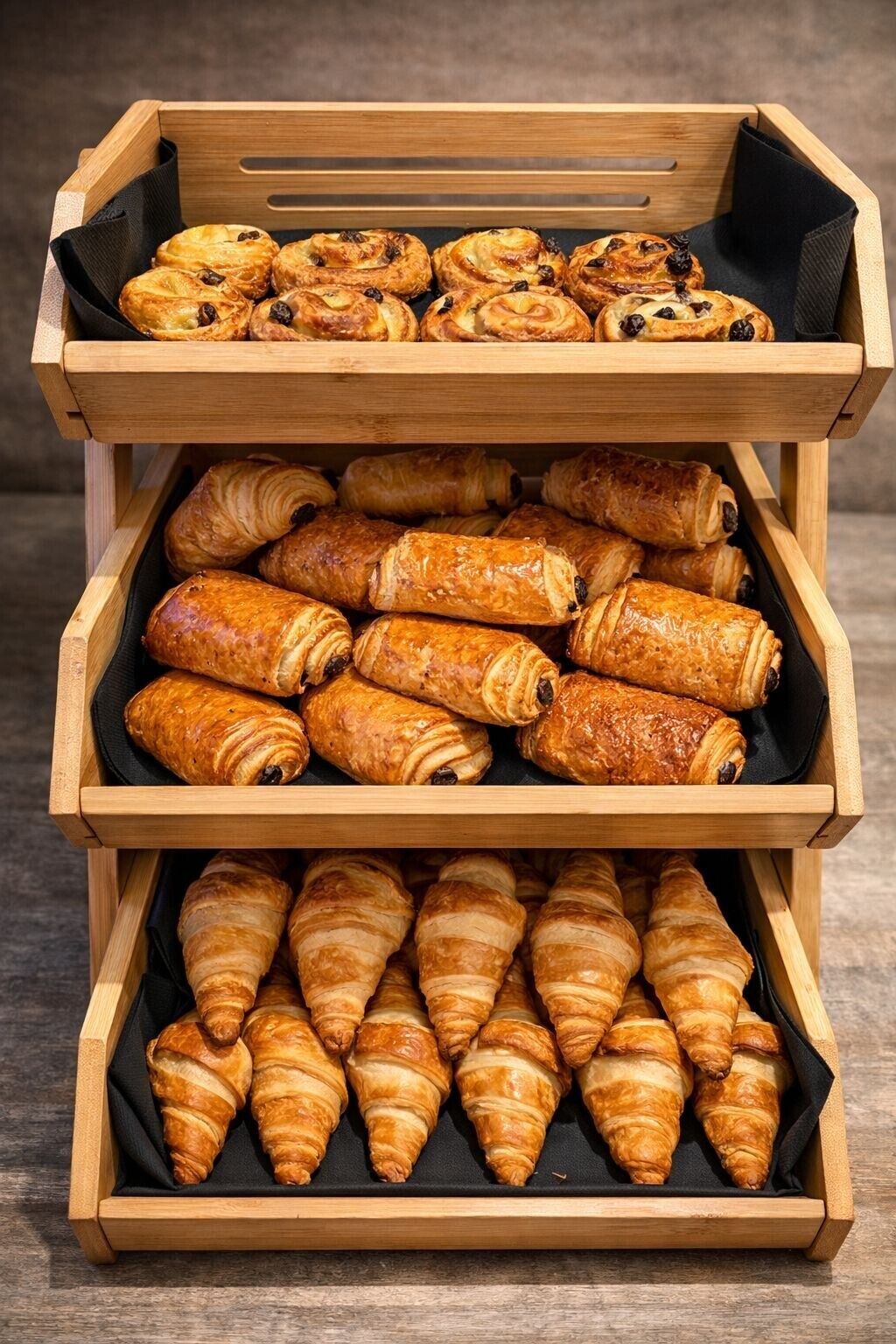 A wooden display case with three tiers of pastries.