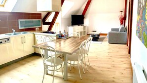 Una cocina moderna con zona de comedor, suelo de madera y televisor.