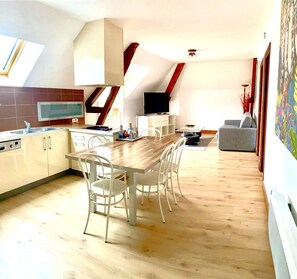 Eine moderne Küche mit Essbereich, Holzboden und Fernseher.
