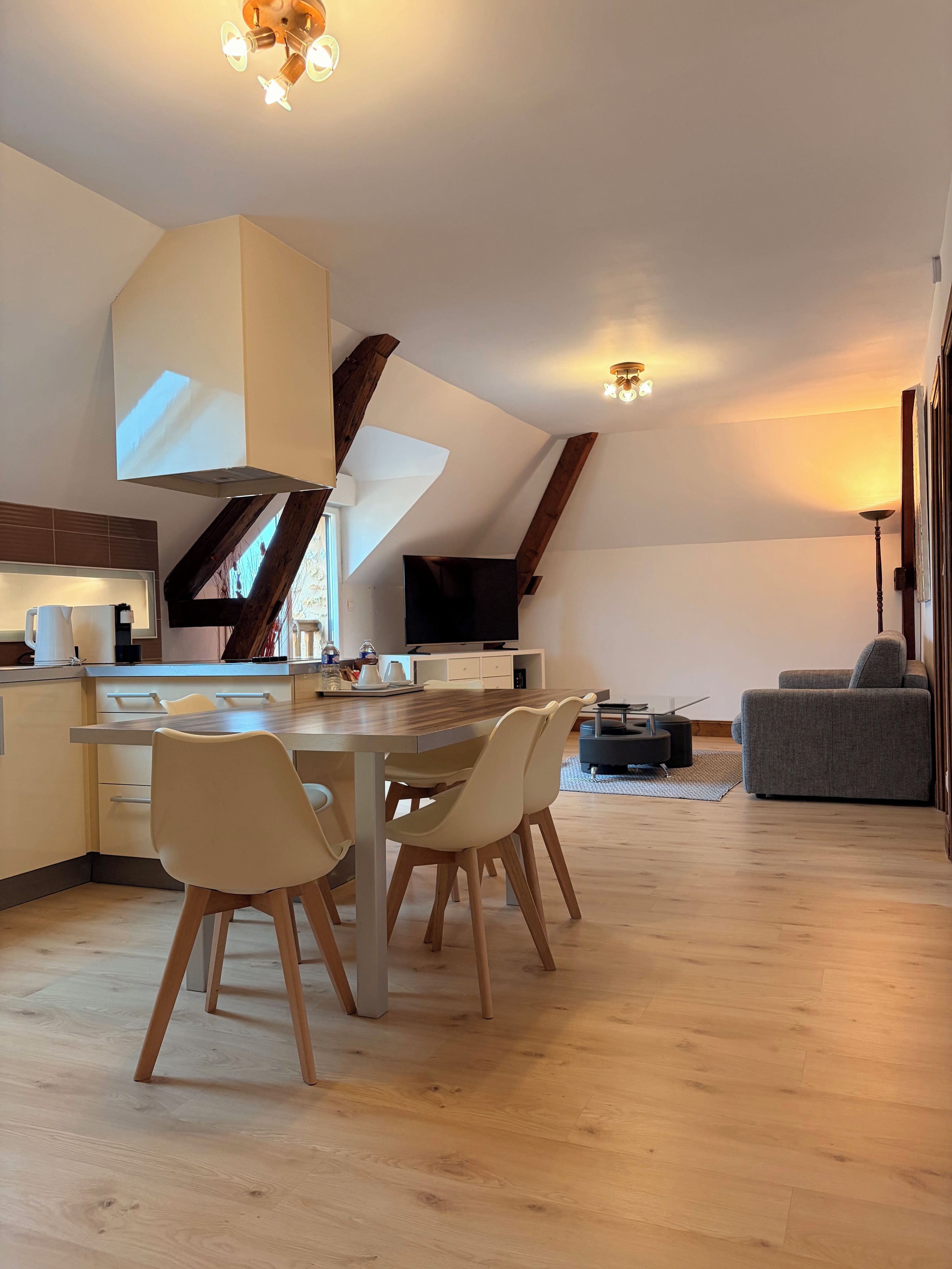 Una cocina moderna con comedor, vigas de madera y un televisor de pantalla plana.