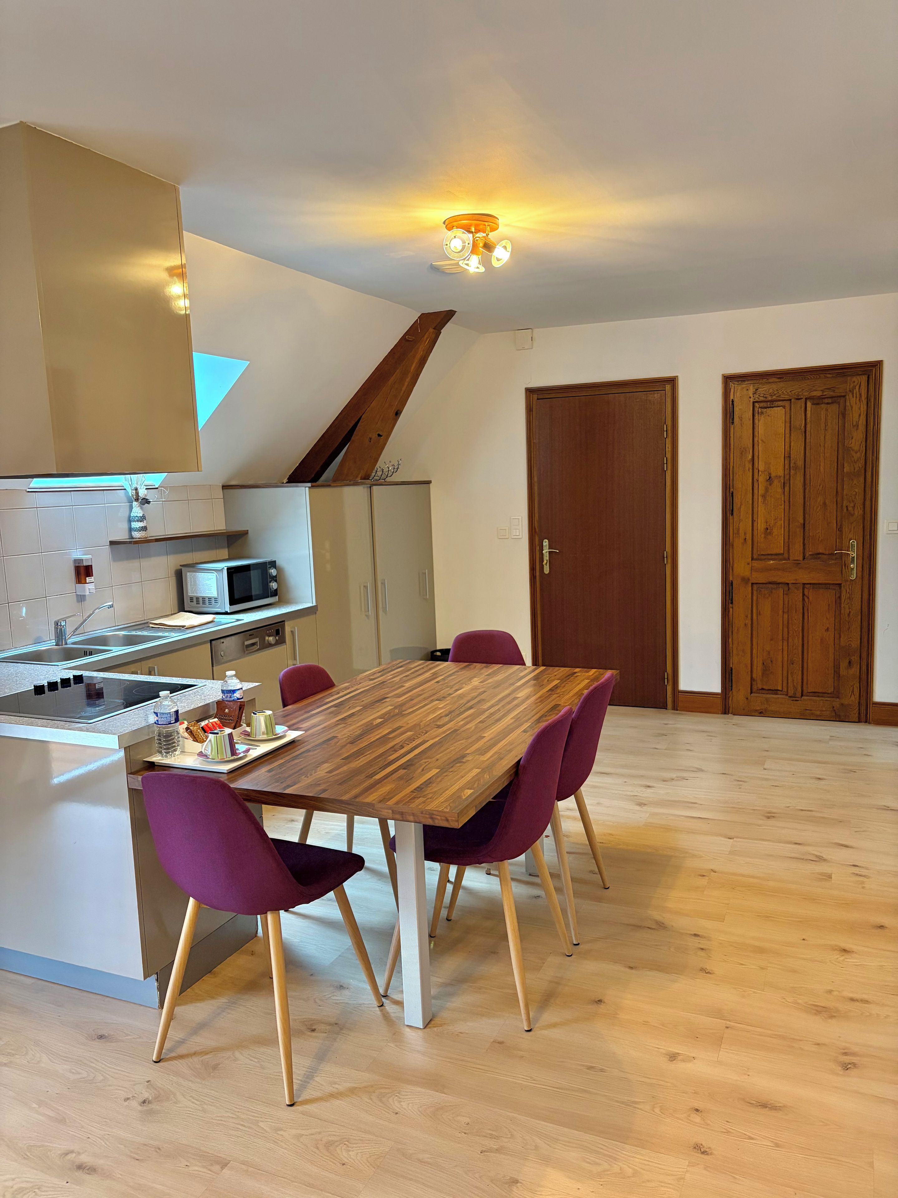 Una cucina moderna con forno a microonde integrato, un tavolo da pranzo in legno con sedie viola e pavimento in legno.