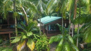 Una estructura de madera con techo verde rodeada de frondosa vegetación tropical.