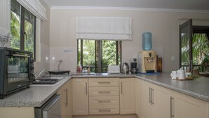 Una cocina con tostadora, cafetera y dispensador de agua.