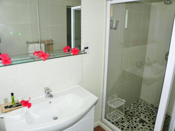 A bathroom with a white sink, mirror, and shower area.