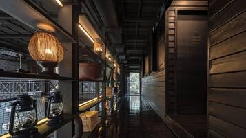 A corridor with a wooden floor, a metal railing on the left, and a staircase on the right.
