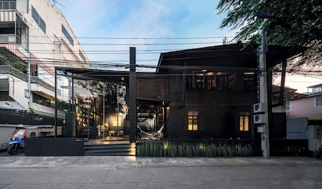 A modern building with a covered entrance, a hammock, and a taxi parked outside.