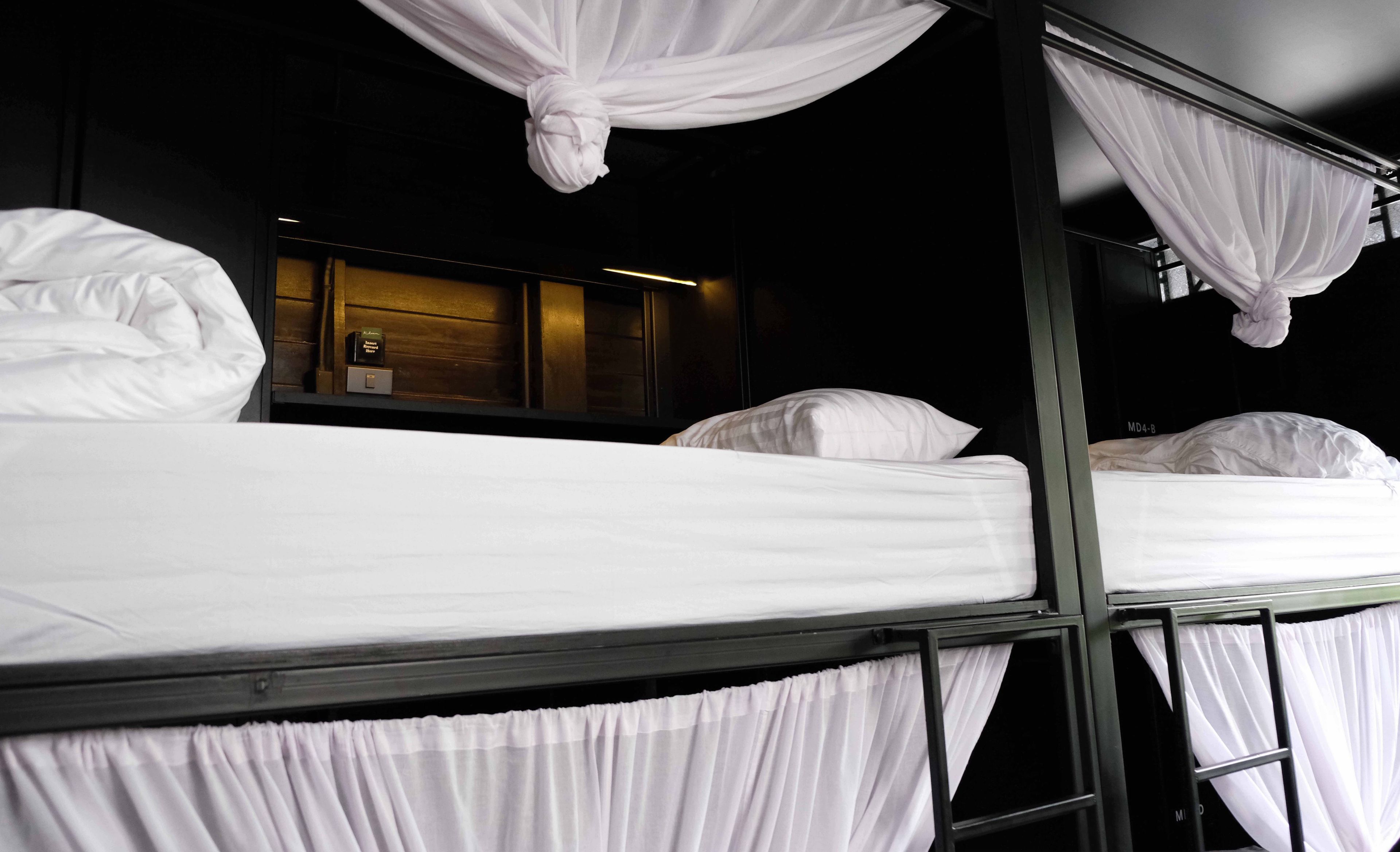 Habitación con literas, ropa de cama blanca y cortinas.