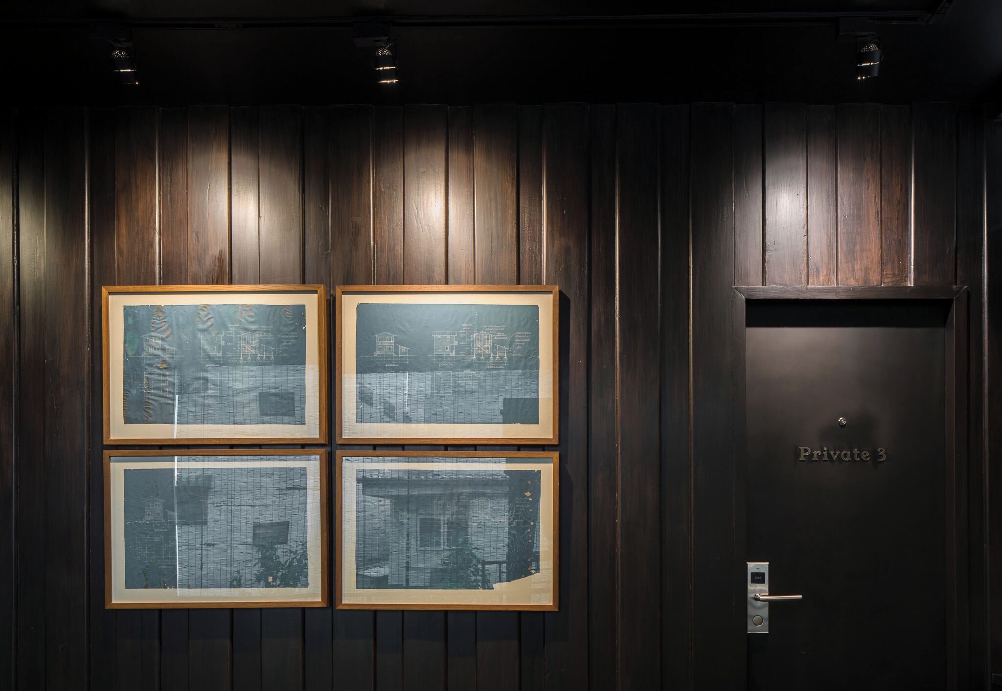 A dark wooden wall with four framed photographs and a door labeled "Private 3".