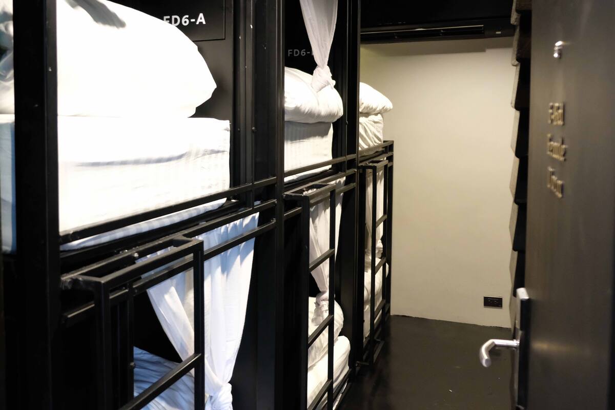 A dormitory room with bunk beds, a wardrobe, and a door with a lock.