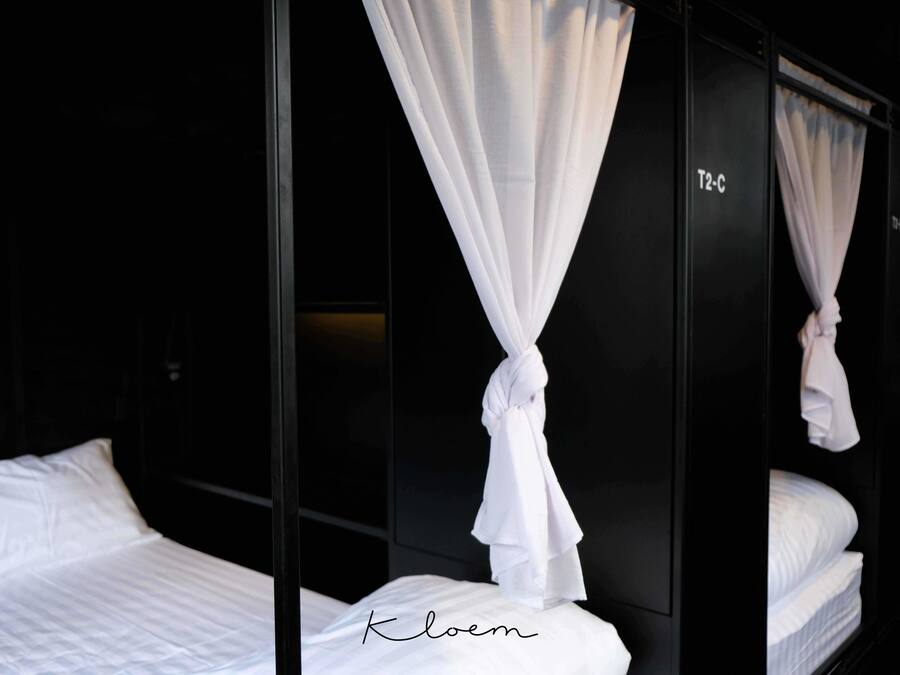 A hotel room with a bed, white curtains, and a black wardrobe.