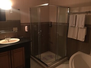A modern bathroom with a glass shower enclosure, a sink, and a toilet. - The Allen Rose (Nairobi)