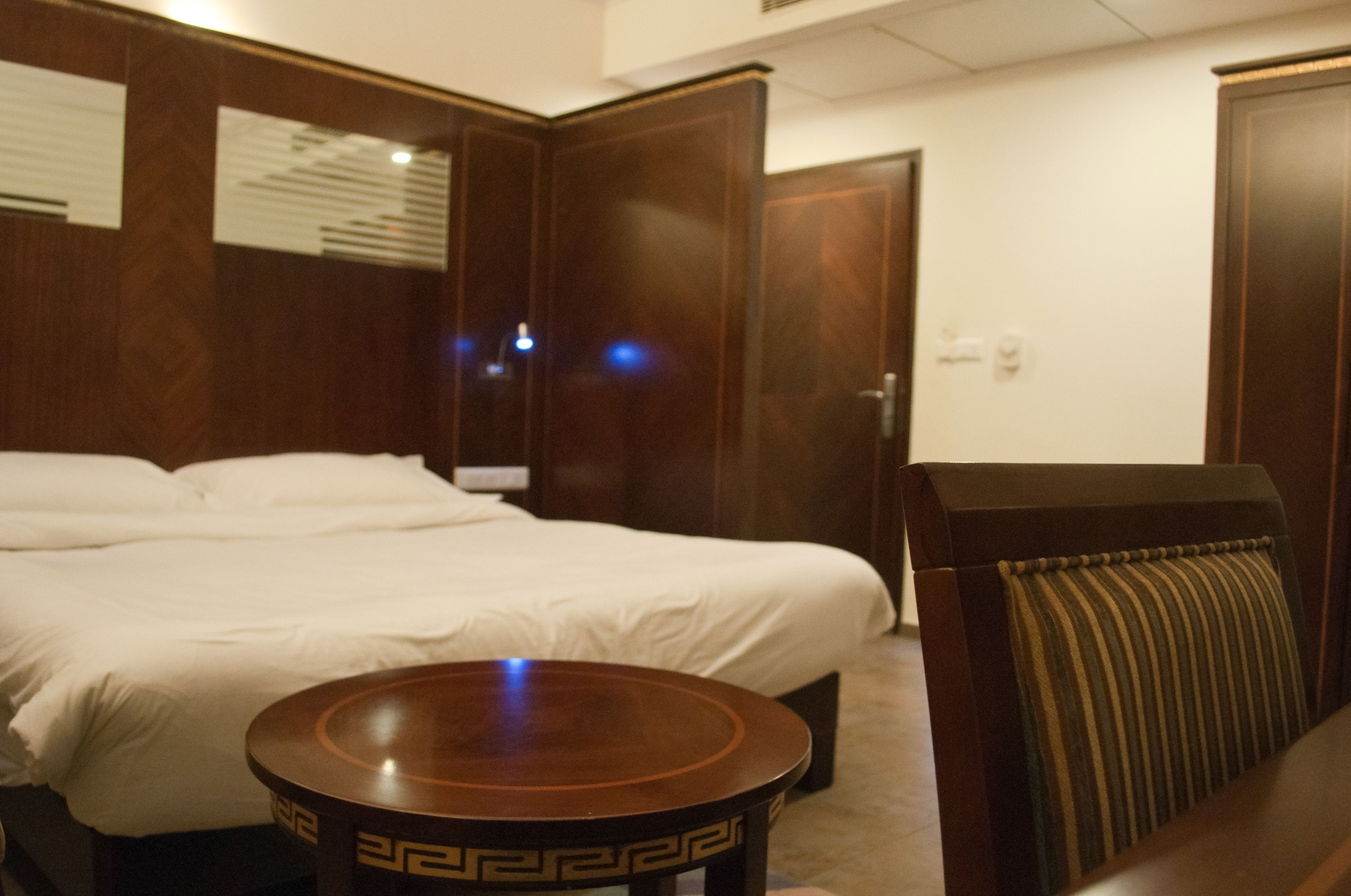 Une chambre d’hôtel avec un grand lit, une table ronde en bois et une chaise à rayures.
