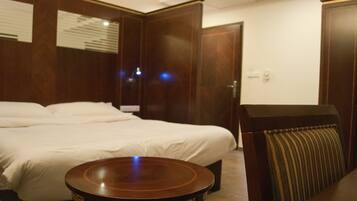 Une chambre d’hôtel avec un grand lit, une table ronde en bois et une chaise à rayures.