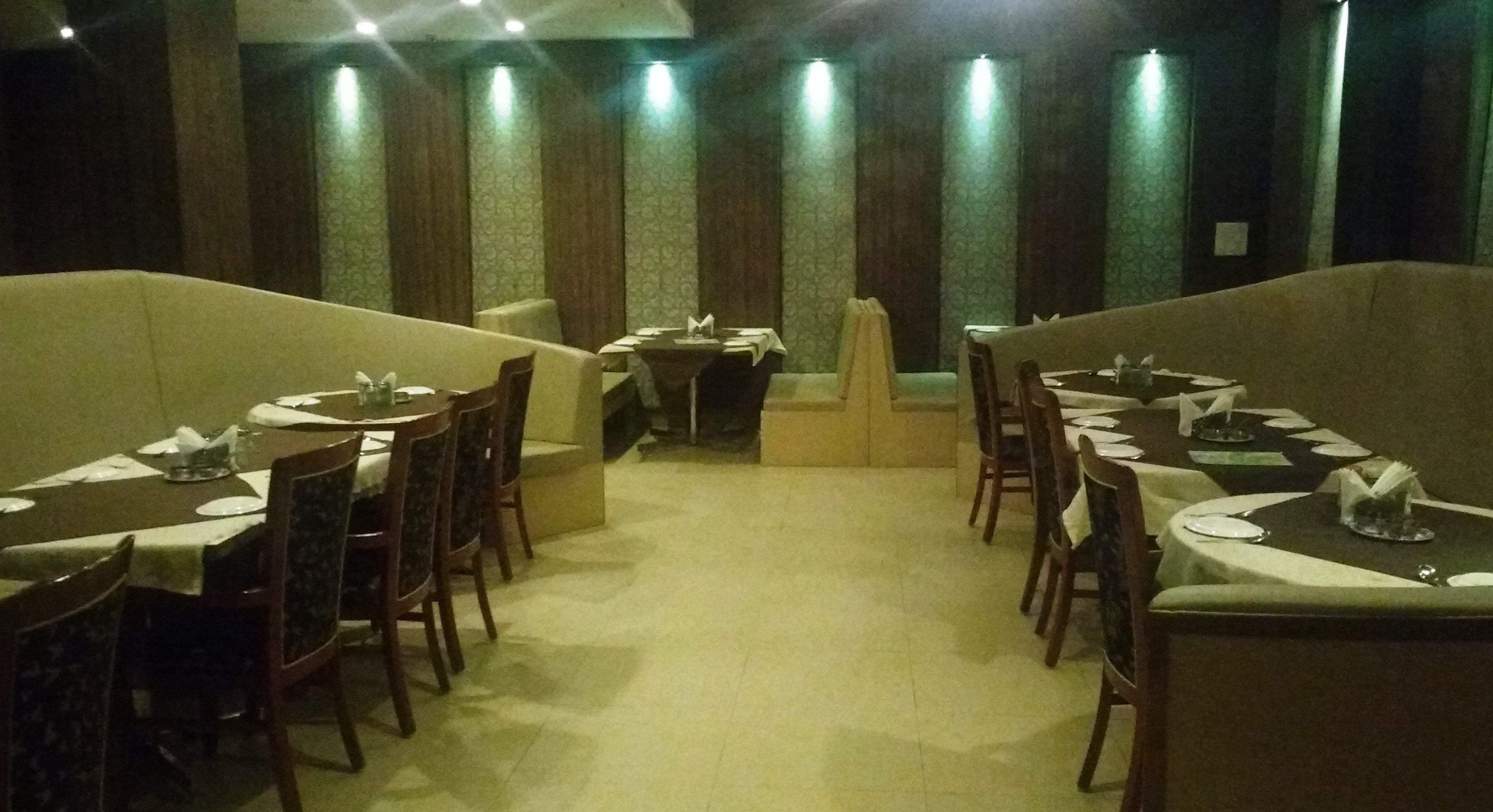 A restaurant with multiple tables and chairs, arranged in a U-shape.