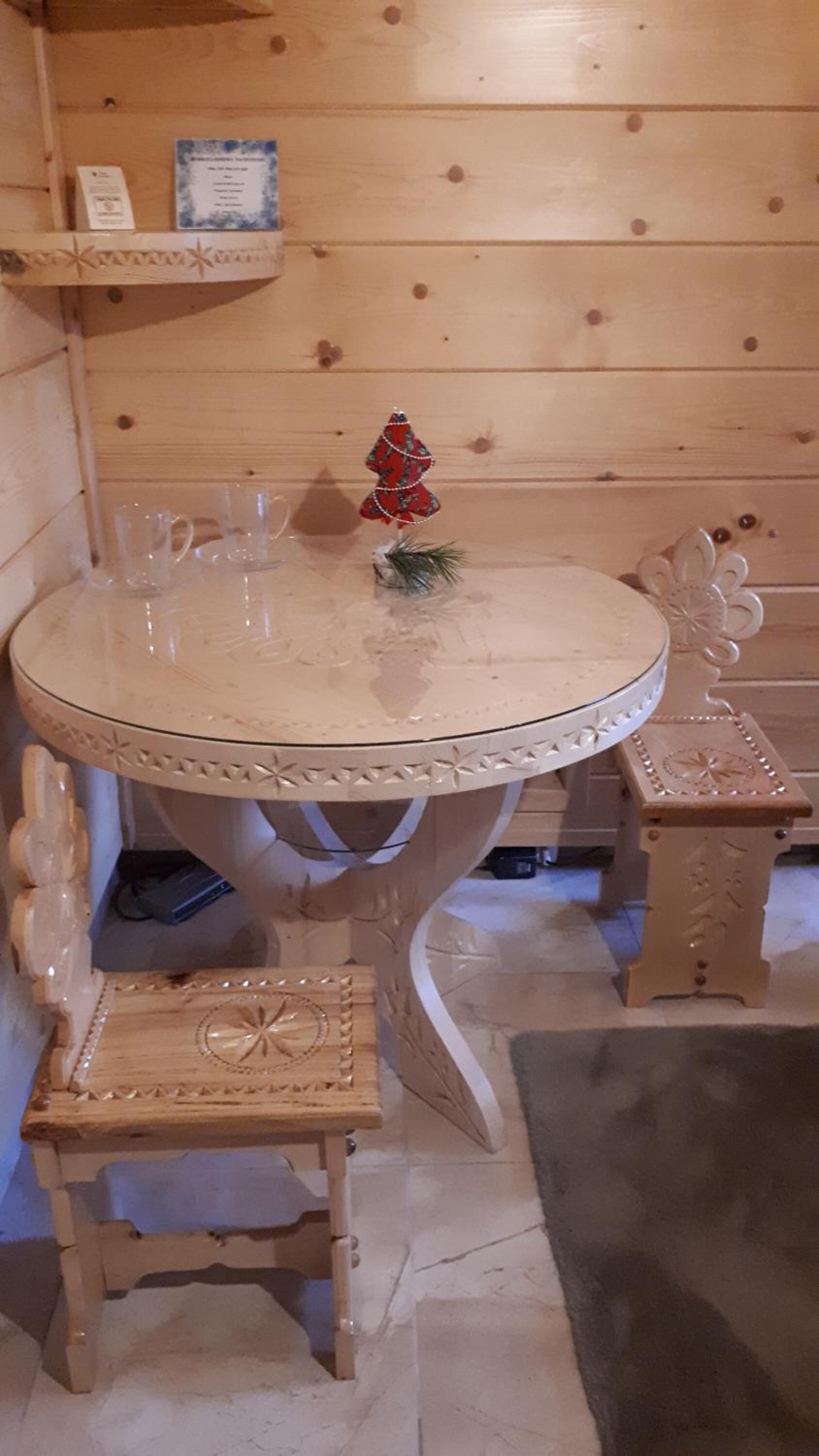 A round table with a decorative edge, a small wooden stool, and a Christmas tree ornament.