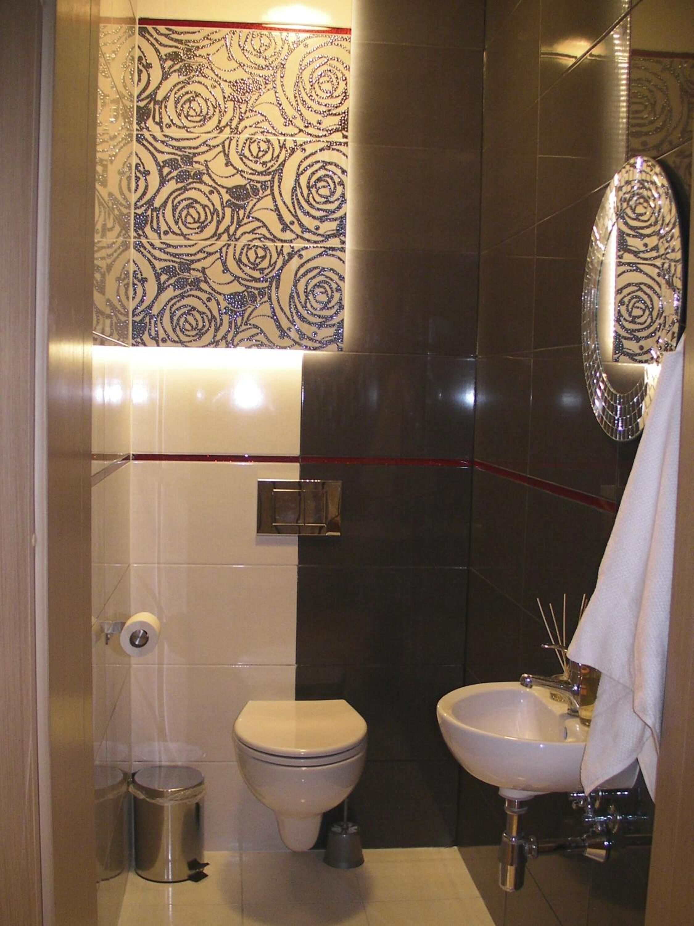 A bathroom with a toilet, sink, and mirror.