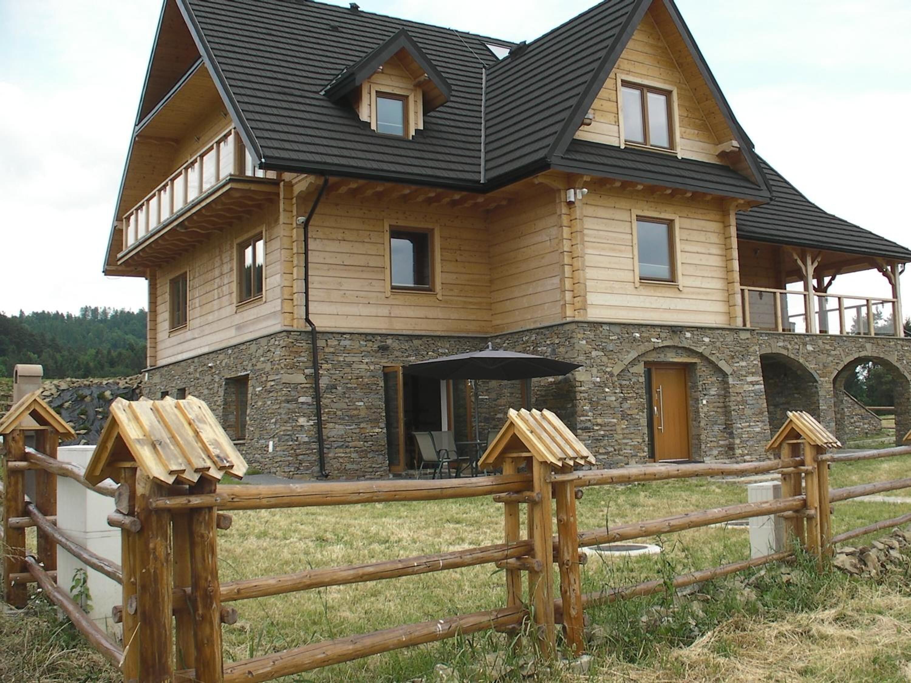 Una casa grande de madera con cimientos de piedra, varias ventanas y un balcón.