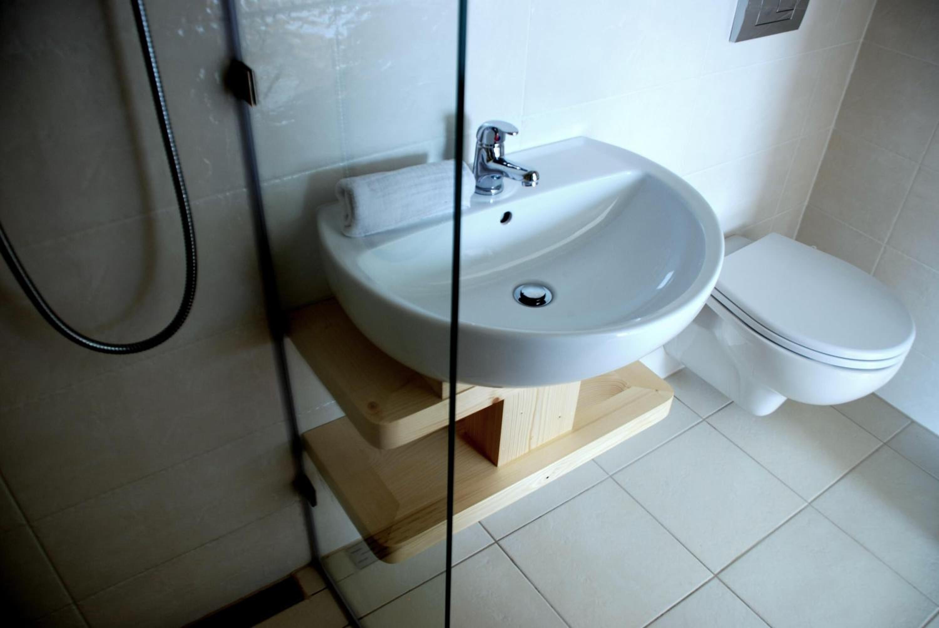 Une salle de bain avec un lavabo blanc, des toilettes et une douche à parois de verre.