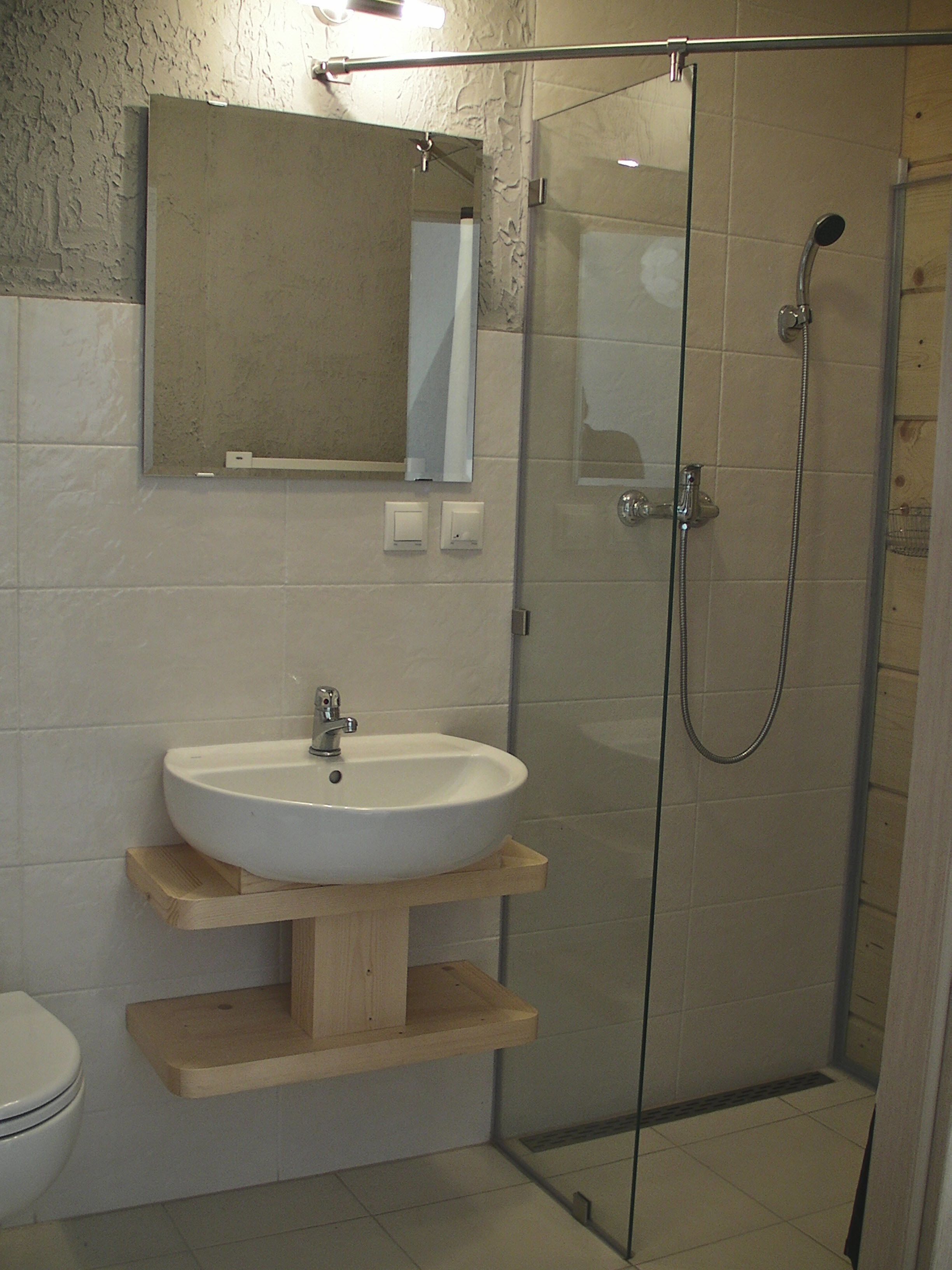 A bathroom with a white sink, a mirror above it, and a glass-enclosed shower.