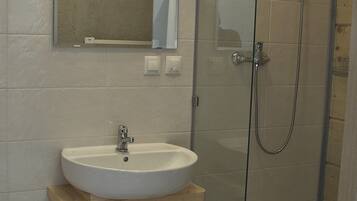 A bathroom with a white sink, a mirror above it, and a glass-enclosed shower.