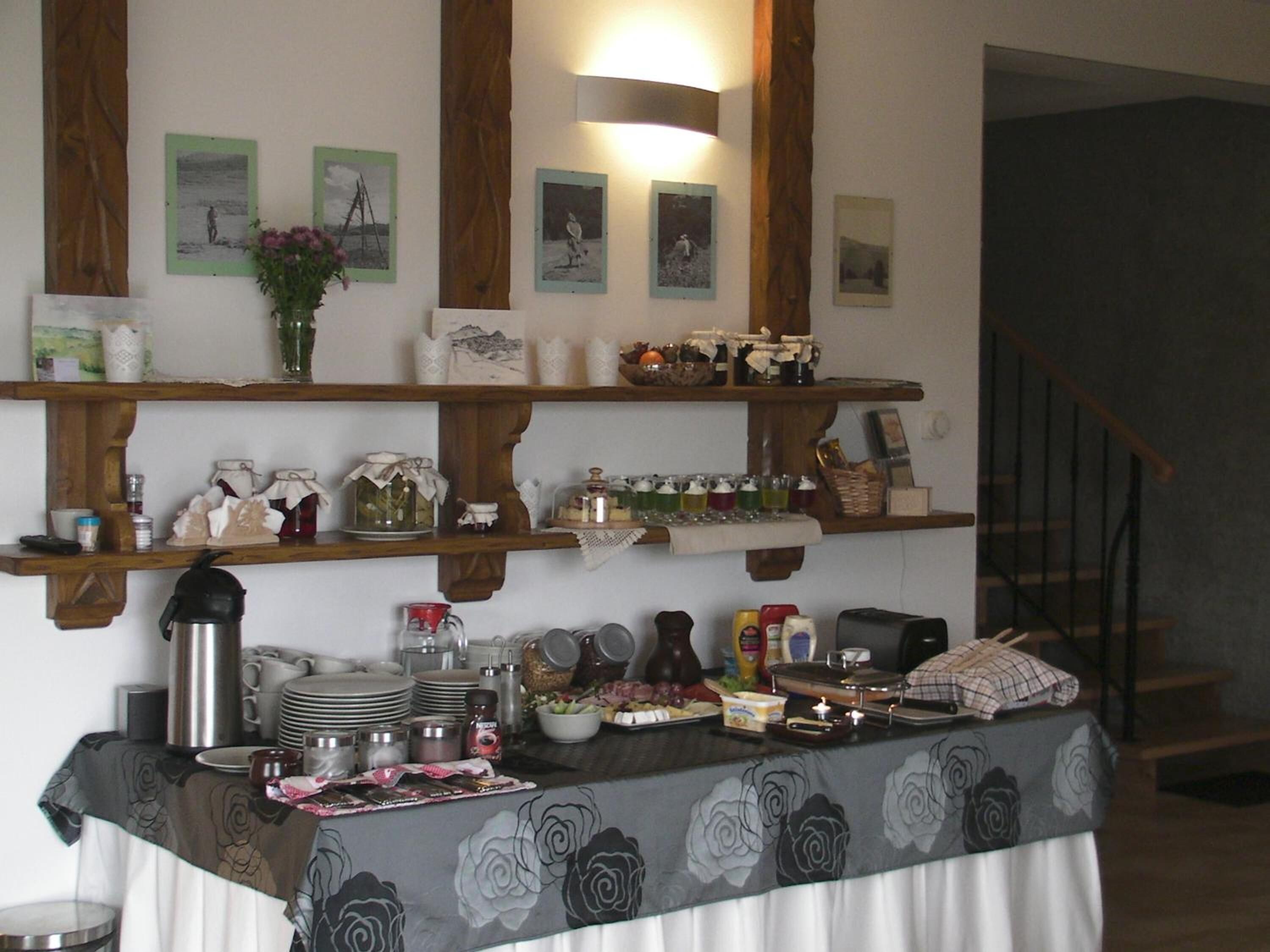 A dining area with a table set for a meal, surrounded by wooden shelves with various items.