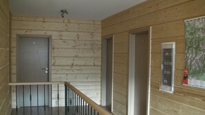 Interior de madera con una escalera, una puerta y un ventanal con un mapa.