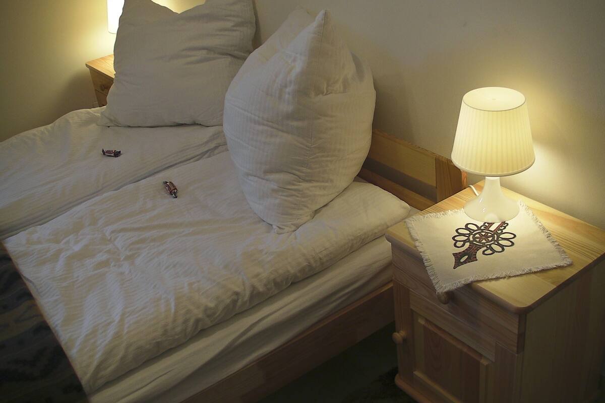 A neatly made bed with pillows, a bedside lamp, and a decorative pillow on the nightstand.