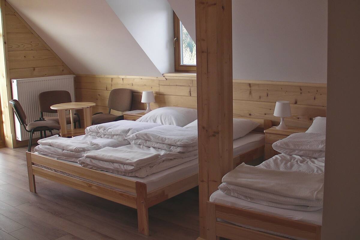 A cozy room with a wooden bed, a small table, and a chair.