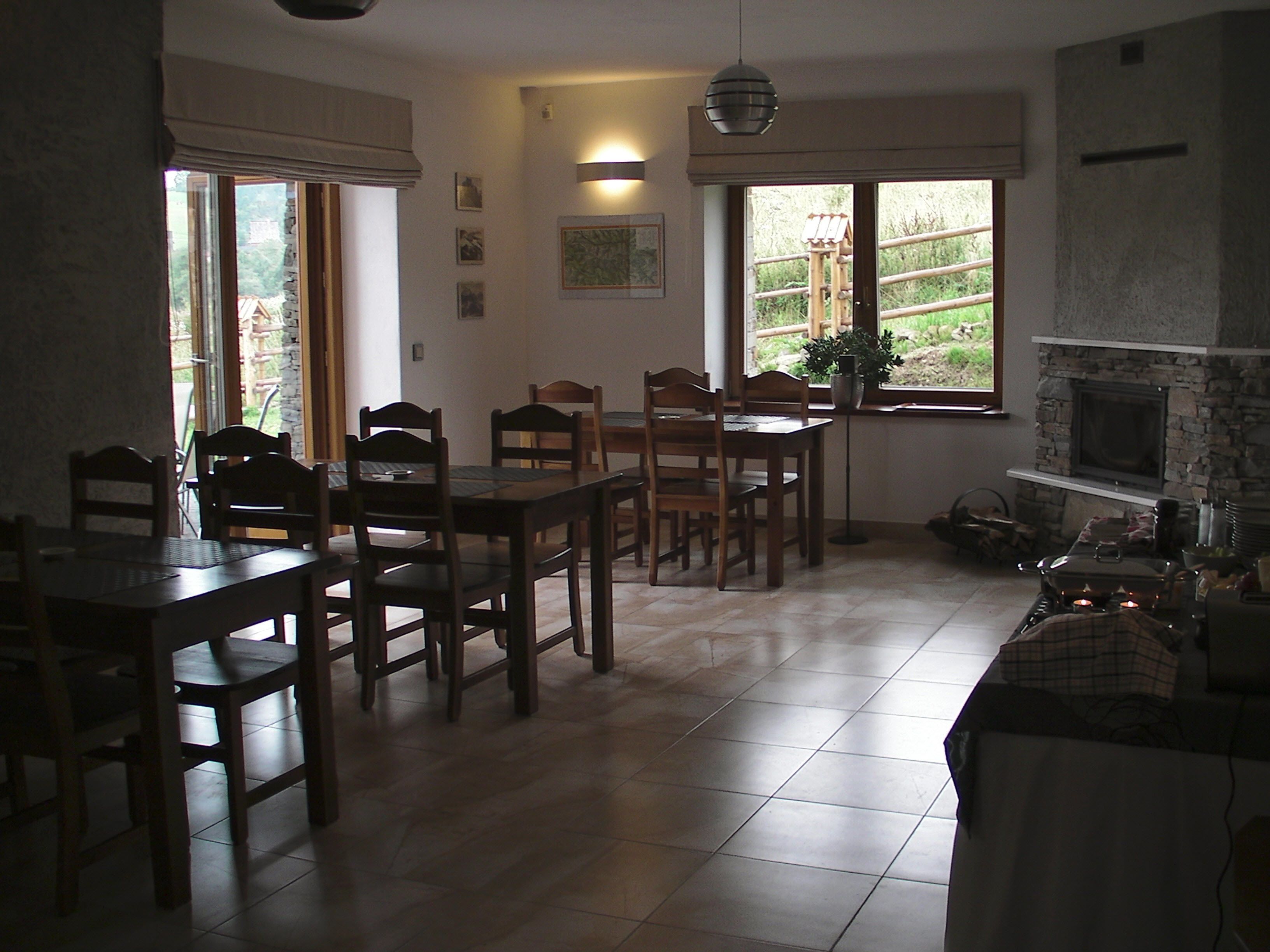 A spacious kitchen with a dining area, large windows, and a stone fireplace.