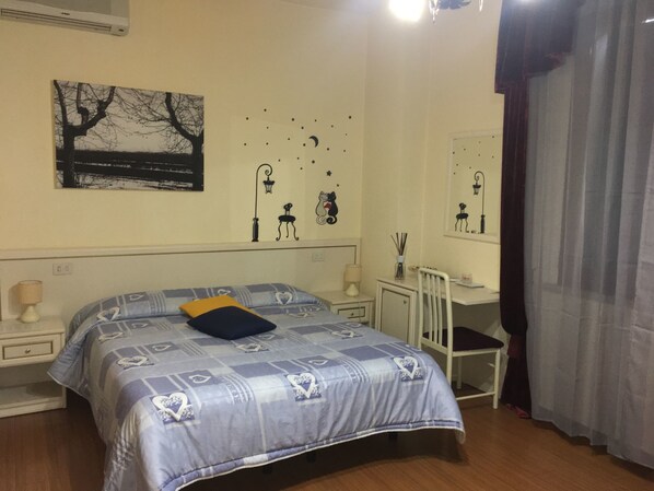 A bedroom with a bed, bedside tables, a desk, and a chair. There are wall decorations including a tree, stars, and a cat. - La Stregatta B&B (Fucecchio)