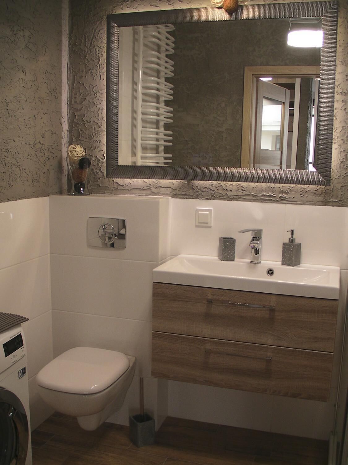 Un bagno con il water, un lavandino con uno specchio sopra e una zona doccia.