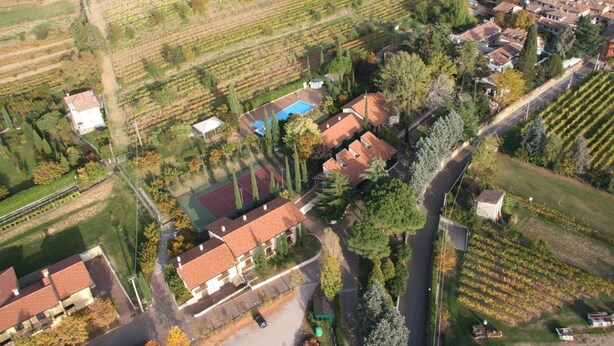 An aerial view of a residential area with houses, a swimming pool, and agricultural fields.