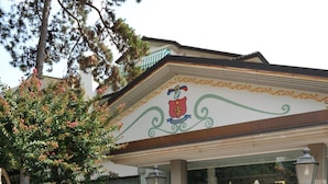 Entrada de un edificio con un emblema decorativo, un banco y un perro acostado en el suelo.