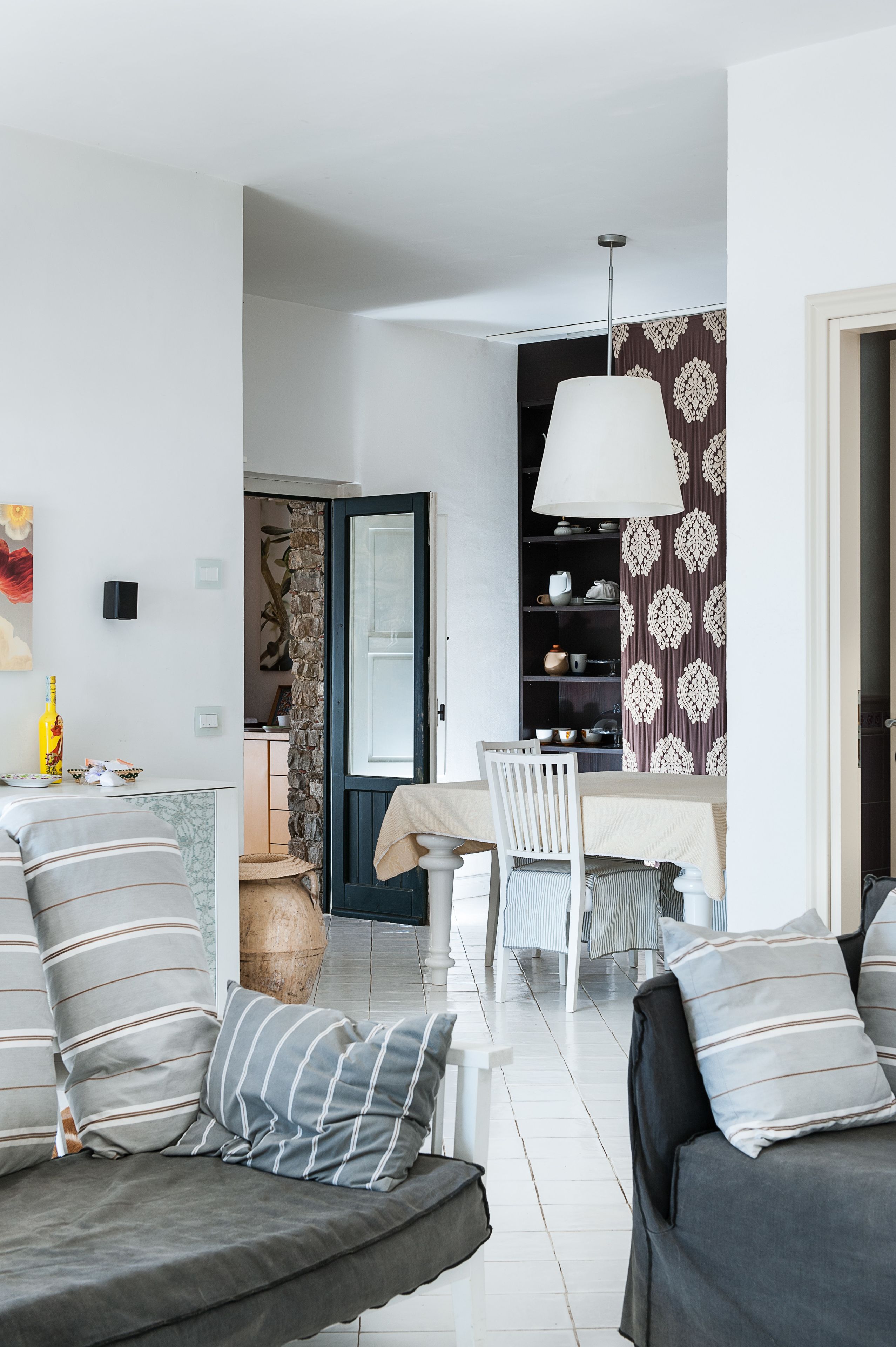 Ein modernes Wohnzimmer mit einer Sofagarnitur, einem Esstisch mit Stühlen und einer dekorativen Lampe.