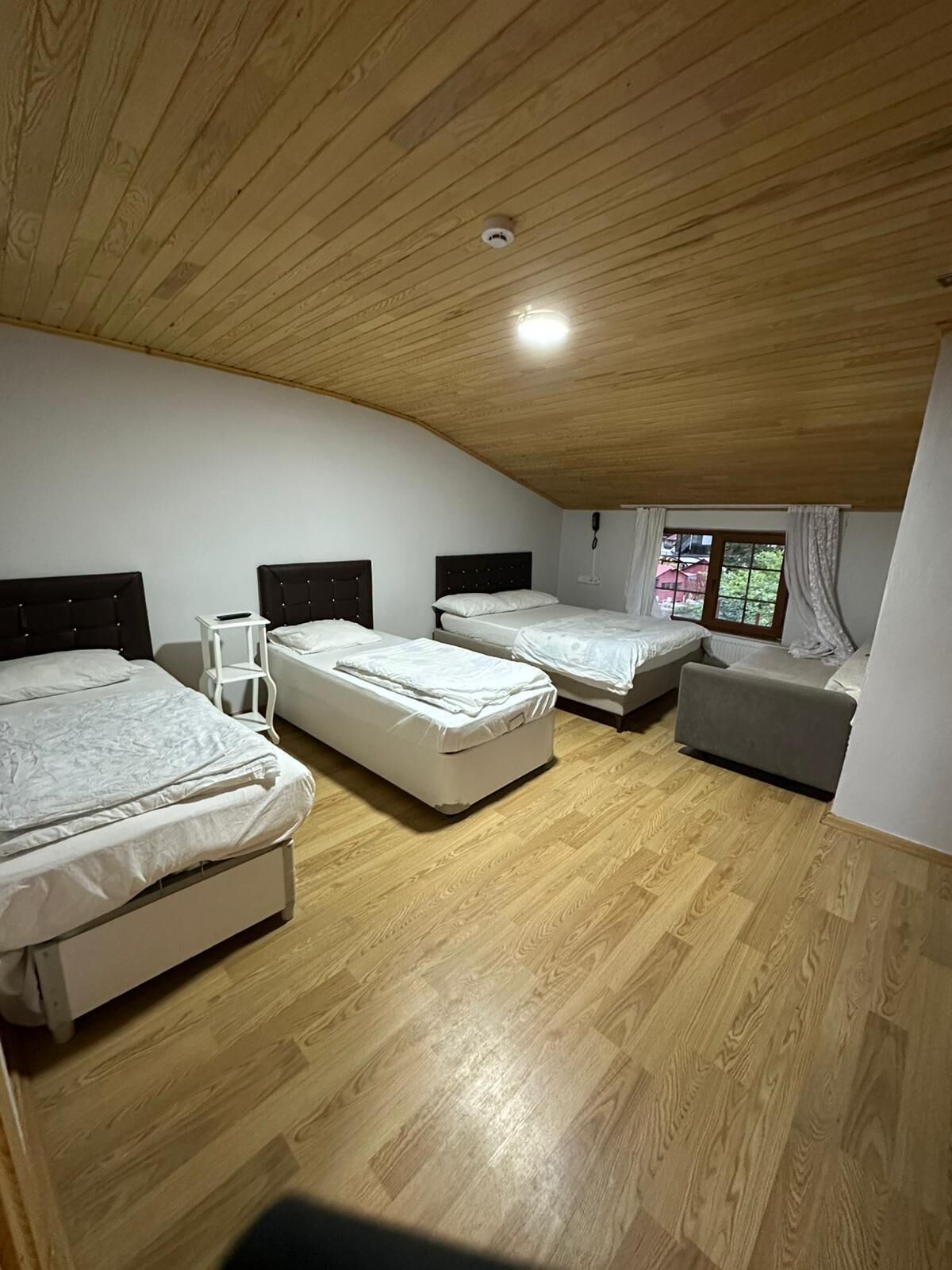 Un dormitorio con tres camas, una mesita y una ventana con cortinas.