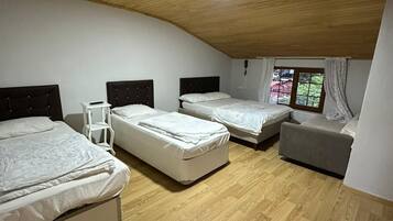 Un dormitorio con tres camas, una mesita y una ventana con cortinas.
