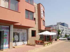 Een hotel met een opvallend bord, terras en een etalage met advertenties.