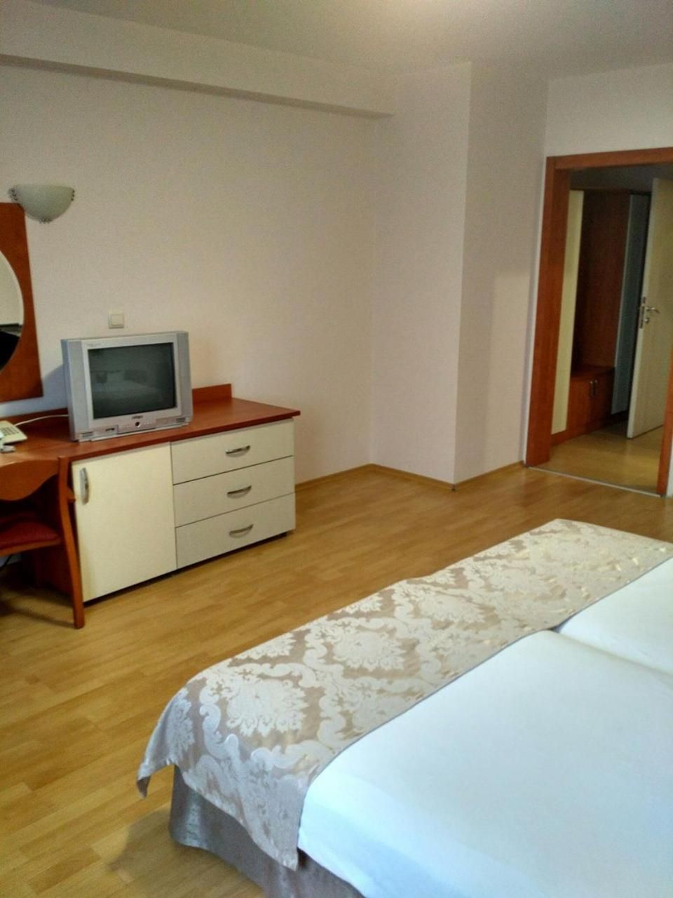 Une chambre à coucher avec un lit, un bureau avec une télévision et un miroir.