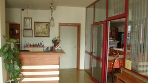 Una cocina con encimera de madera, un lavamanos y una planta en maceta. Hay una puerta con la etiqueta "WC" y una zona de comedor con mesas y sillas.