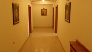 Un pasillo con suelo de baldosas, puertas de madera y cuadros en las paredes.