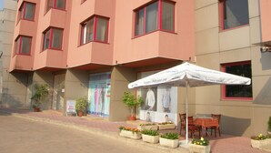 A multi-story building with a flat facade, red-framed windows, and a signboard advertising a local event. - Hotel Philippopolis (Plovdiv)