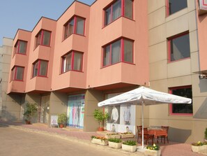 Un edificio de varios pisos con fachada plana, ventanas de marco rojo y un cartel anunciando un evento local.
