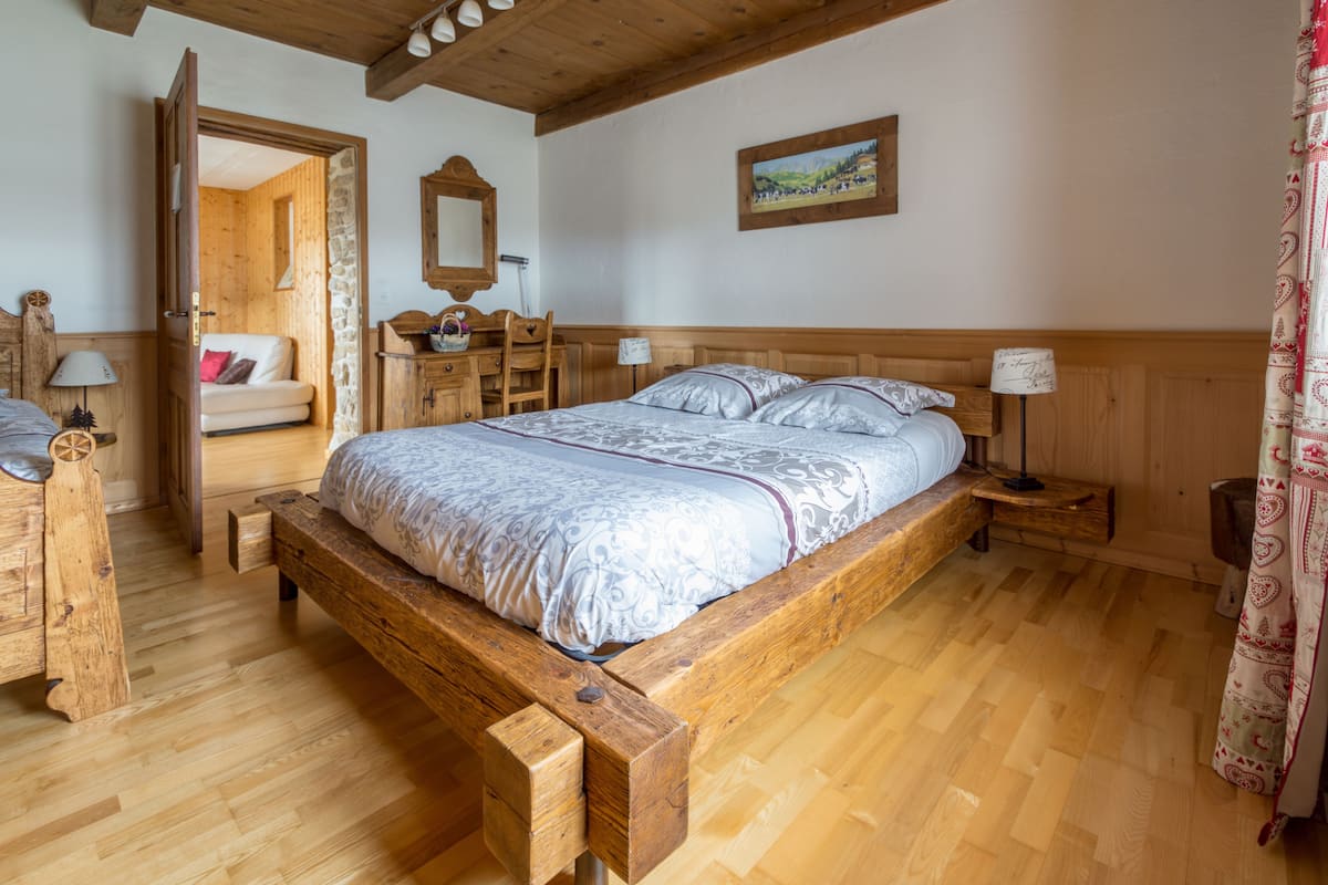 Un lit en bois avec une tête de lit, une table de chevet en bois, un banc en bois, une commode en bois et une chaise en bois.